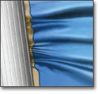 A shiny blue fabric being pressed against a ridged metal surface, creating gathered folds where the fabric meets the metal edge.