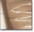 A sheet of dough is being rolled out on a flat surface, with traces of flour visible on the dough and countertop.