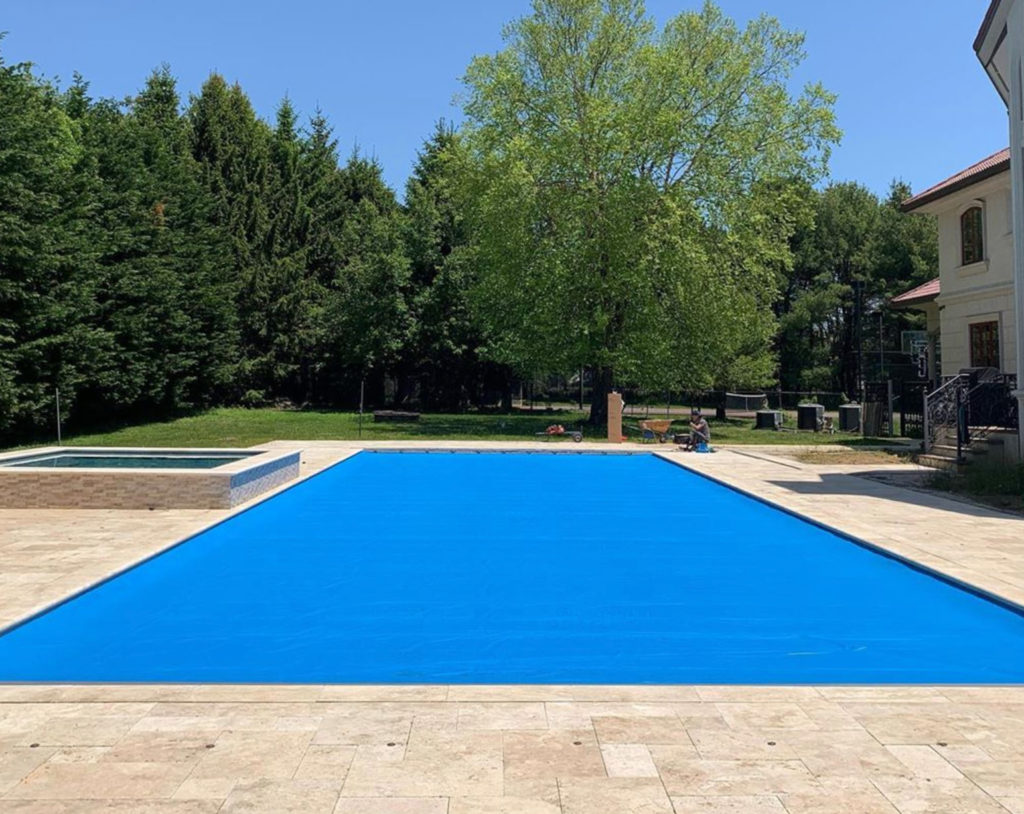 Cover-Pools Royal Blue automatic pool cover with tan stone around the pool deck