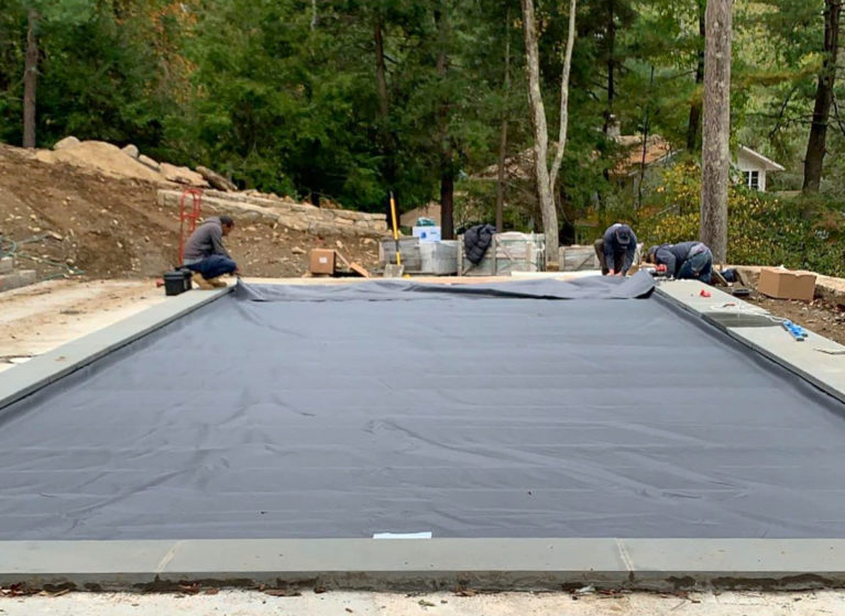 New Pool Cover installation- Three CoverSafe technicians working to install a brand new charcoal automatic pool cover on a new in-ground pool